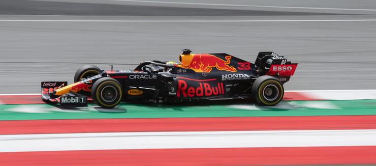 Red Bull Formula 1 racing car photographed during a race in 2021. The car is mostly black with a red bull painted in the top part. The driver is Max Verstappen, although you can’t see that it’s him due to the helmet he’s wearing.